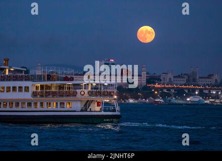 Istanbul, Turkey. 11th Aug, 2022. With the full moon appearing in the sky, a city lines ferry seen cruising at the Bosphorus. Boats passing through the Bosphorus and city line ferries were seen in Istanbul with the full moon appearing during the sky in the evening hours. Credit: SOPA Images Limited/Ģ����ý Live News Stock Photo