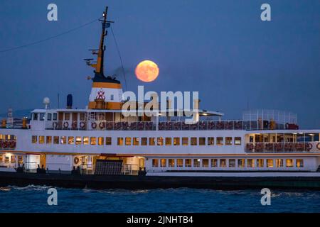 Istanbul, Turkey. 11th Aug, 2022. With the full moon appearing in the sky, a city lines ferry seen cruising at the Bosphorus. Boats passing through the Bosphorus and city line ferries were seen in Istanbul with the full moon appearing during the sky in the evening hours. (Photo by Onur Dogman/SOPA Images/Sipa USA) Credit: Sipa USA/Ģ����ý Live News Stock Photo