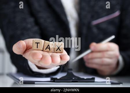 Man holding on palm tax word collected of wooden blocks letters Stock Photo