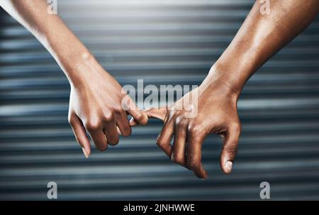 Promise well work hard at it. Closeup shot of a sporty couple holding each others little finger against a grey background. Stock Photo
