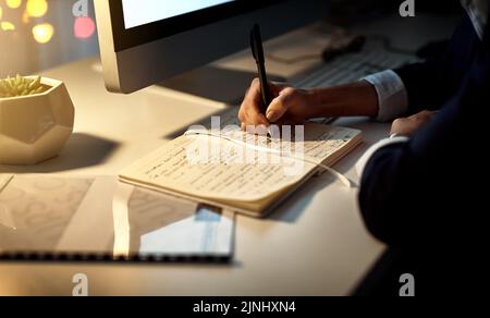 Planning her next move. Closeup shot of a businesswoman writing notes in an office at night. Stock Photo
