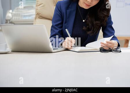 Close-up shot of unrecognizable white collar worker taking notes while working on start-up project at modern office Stock Photo