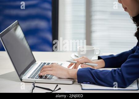 Close-up shot of hard-working financial manager sitting in front of laptop and finishing annual accounts, office interior on background Stock Photo