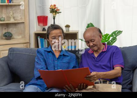 Senior asian couple talking happy planing retirement insurance health care contract on sofa. Stock Photo