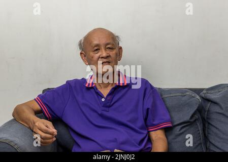 Asian elderly man portrait sitting on the sofa at home. Stock Photo