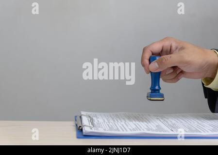 Man stamping approval of work finance banking or investment marketing documents on desk. Stock Photo