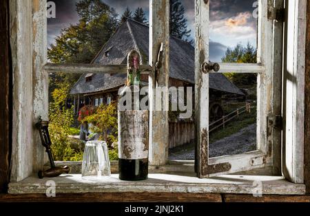 View through rustic wooden window with old wine bottle on a historical water mill Stock Photo