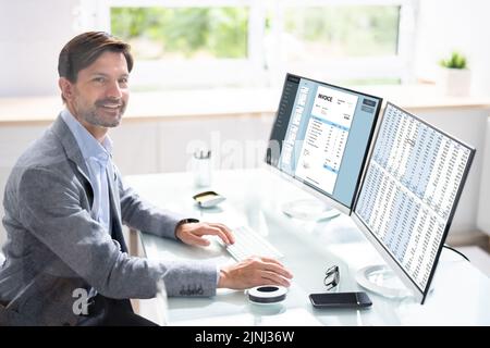 Looking At Invoice And Spreadsheet On Computer At Work Stock Photo