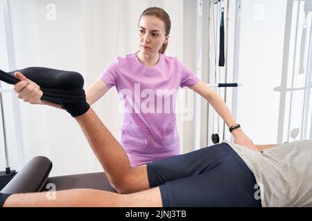 Man undergoing physical therapy procedure in rehabilitation clinic Stock Photo