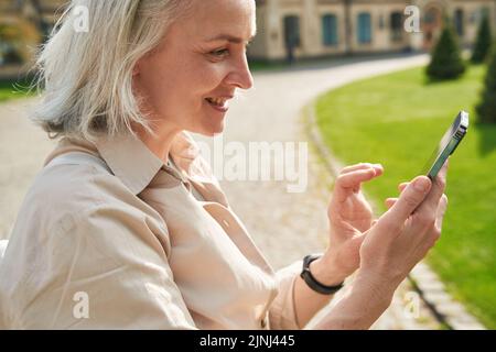 Side view of mature woman using her smartphone outdoors Stock Photo