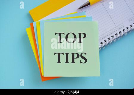 The phrase Top Tips text on sticker note as a reminder, Business concept,blue background. Stock Photo