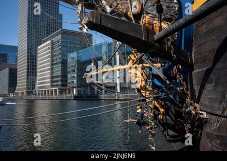 Crew members of the replica sailing ship, Gotheborg, perform repairs and maintenance at the ship's figurehead while docked beneath the high-rise towers at South Quay, Canary Wharf in London Docklands, during its four-day visit to the capital before it continues its two-year around the world expedition to Shanghai, China, on 9th August 2022, in London, England. Londoners are invited to tour the decks of this facsimile of the original ship which sank off the Swedish coast in 1745. Its main cargo would have been tea, porcelain, herbs and silk on the China route. (Photo by Richard Baker / In Pictu Stock Photo