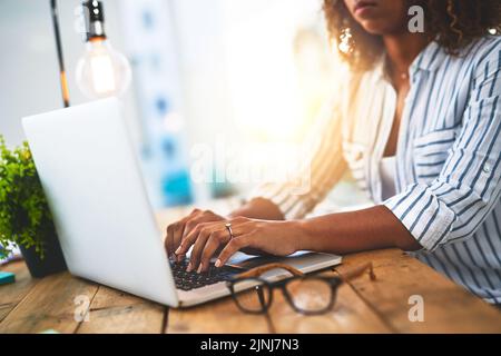 Hands of a woman working with her laptop on a wooden table indoors. Closeup of entrepreneur typing in an open plan home office. Female blog writer Stock Photo
