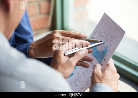 Close-up shot of unrecognizable colleagues gathered together at modern office and analyzing statistic data Stock Photo