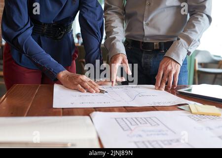 Group of talented managers gathered together at boardroom and brainstorming on joint project, documents lying on wooden table Stock Photo