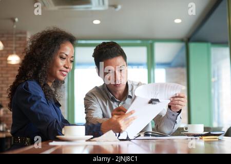 Team of white collar workers gathered together at modern coffeehouse and working together on start-up project Stock Photo
