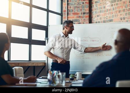 Take a look right here. Businessman doing a presentation in a meeting planning the company growth strategy in an office. Serious male entrepreneur Stock Photo