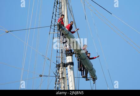 Crew members stand on the yards of the Shabab Oman II, a full-rigged training ship of the Royal Navy of Oman, arrives into Portsmouth Harbour. The ship is a blend of the traditional and modern with state of the art computerised communication systems and navigation equipment, but from the wooden decking upwards, the ship is traditional in terms of her sails and rigging. Picture date: Friday August 12, 2022. Stock Photo