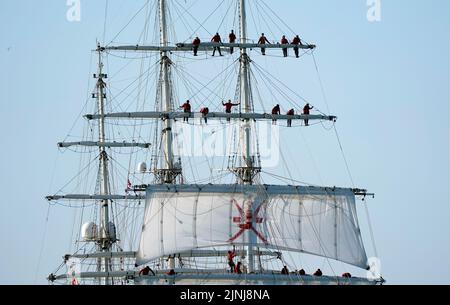 Crew members stand on the yards of the Shabab Oman II, a full-rigged training ship of the Royal Navy of Oman, arrives into Portsmouth Harbour. The ship is a blend of the traditional and modern with state of the art computerised communication systems and navigation equipment, but from the wooden decking upwards, the ship is traditional in terms of her sails and rigging. Picture date: Friday August 12, 2022. Stock Photo