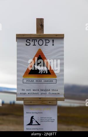 Attention, polar bear. Warning sign against gray sky. Seen in Ny-Alesund, Svalbard, Norway. Stock Photo