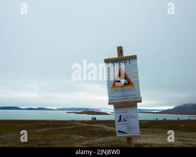 Attention, polar bear. Warning sign against gray sky. Seen in Ny-Alesund, Svalbard, Norway. Stock Photo