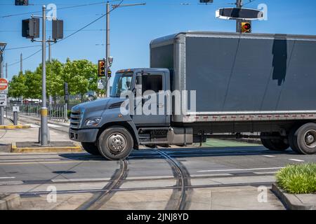 Industrial standard for local deliveries and short haul freights middle duty rigs semi truck with box trailer transporting cargo running on city stree Stock Photo