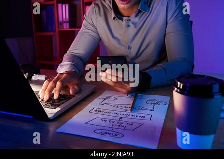 Unrecognizable white collar worker sitting at desk of dim office and dialing number of client while working on ambitious project, close-up shot Stock Photo