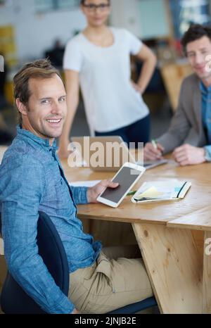 Smiling marketing manager browsing the internet on a digital tablet in an office. Handsome and happy professional researching creative ideas to Stock Photo