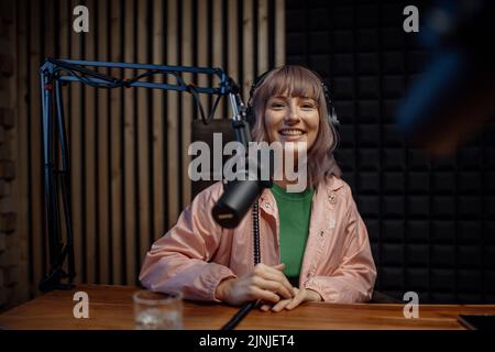 Portrait of female radio host speaking in microphone while moderating a live show Stock Photo