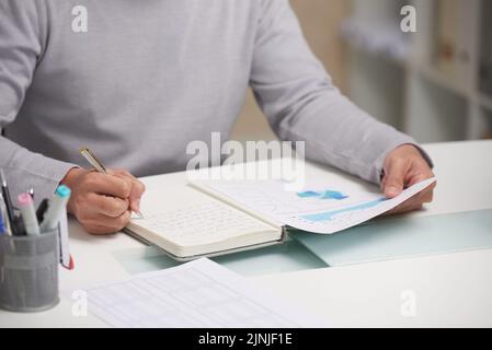 Cropped image of financial manager analyzing diagram and taking notes Stock Photo