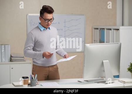 Vietnamese young entrepreneur reading document in his hands Stock Photo