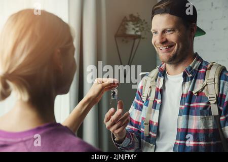 solo traveller backpacker gets keys from room owner. travel short term rent, couchsurfing Stock Photo