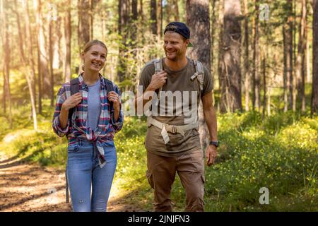 young couple ⁬with backpacks on a hike in forest. backpacking trip, summer adventure vacation Stock Photo