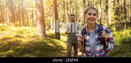 young travel couple with backpacks on nature adventure hike in forest. banner with copy space Stock Photo