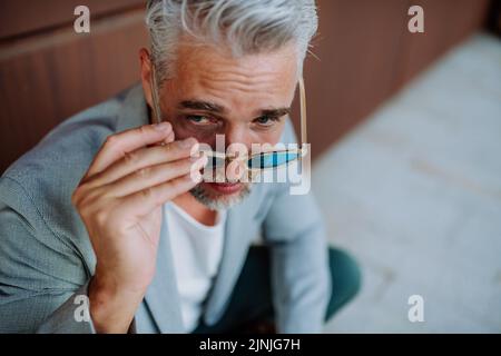 Portrait of successful happy businessman wearing causal clothes and sunglasses in summer in street looking at camera. Stock Photo