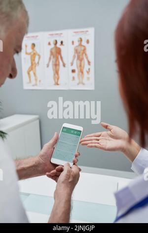 Senior man showing health application in his smartphone to doctor Stock Photo
