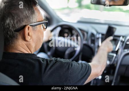 Senior behind the steering wheel using navigation and looking for directions Stock Photo