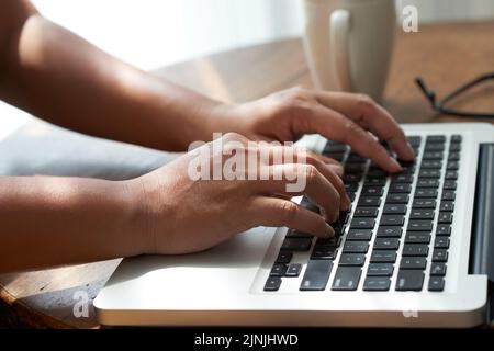 Close-up shot of unrecognizable entrepreneur sitting at office desk and working on visual presentation with help of laptop while preparing for important negotiations with business partner Stock Photo