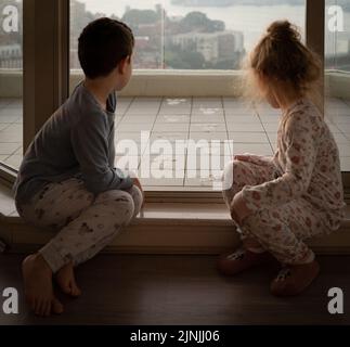 A back view of two kids looking out the Easter Bunny's footprints on the balcony, Sydney, Australia Stock Photo