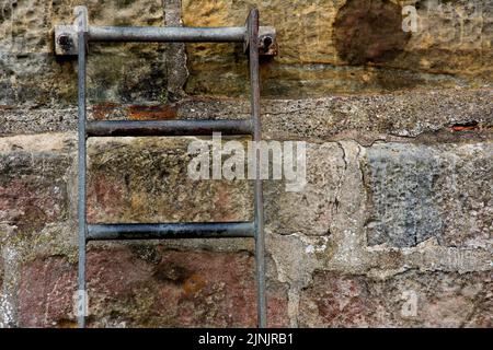 Old access ladder bolted to a harbour wall Stock Photo