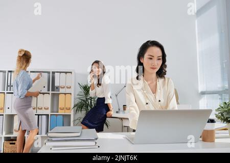 Pretty Chinese business lady working on laptop in office Stock Photo