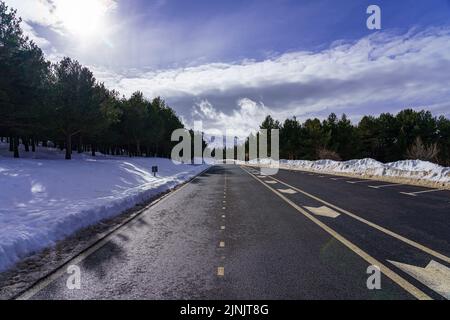 Mountain road with snow and fog on sunny day. Stock Photo