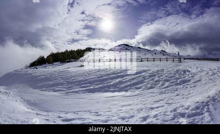 High mountain snowy landscape with sun rays and sky with clouds. Stock Photo