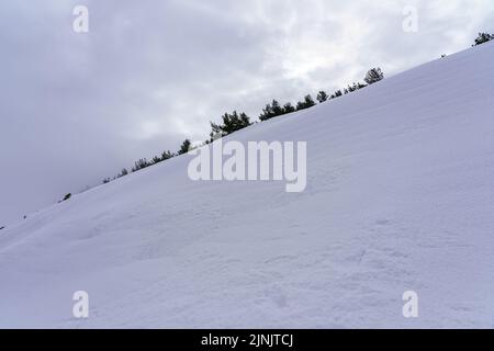 snow-covered mountain slope with clouds. Snow texture. Stock Photo