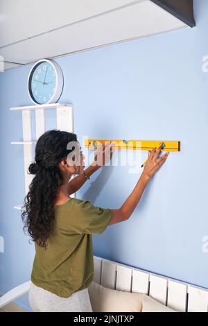 Young woman using construction level to measure the wall Stock Photo