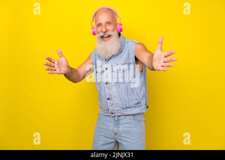 Photo of cool funny retired guy wear jeans waistcoat listening headphones dancing isolated yellow color background Stock Photo