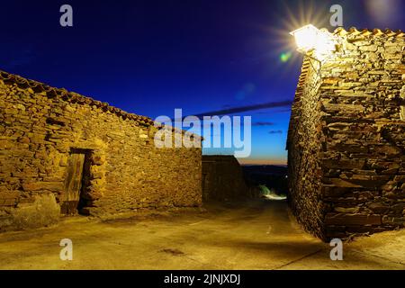 Alley of old stone houses with lamppost and sunset in the sky. Stock Photo
