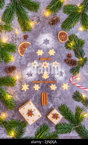 Christmas sweets and cookies in form of christmas tree placed on gray desk with pine cone and branch on the side. Winter and christmas decorations, sm Stock Photo
