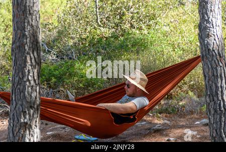 A view of a man relaxing in a hammock, using laptop computer Stock Photo