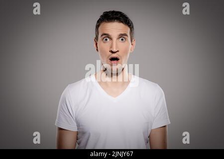 A shocked man with eyes and mouth wide open starring right into camera Stock Photo